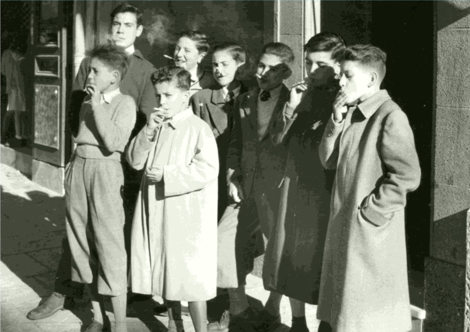En la imatge, un grup de joves fumant amb fruïció cigarretes de matafaluga, o altres herbes aromàtiques, el 8 de desembre de 1954. Foto ArxiuHFidelFita: Jaume Codoñés (atribuït), registre 5352