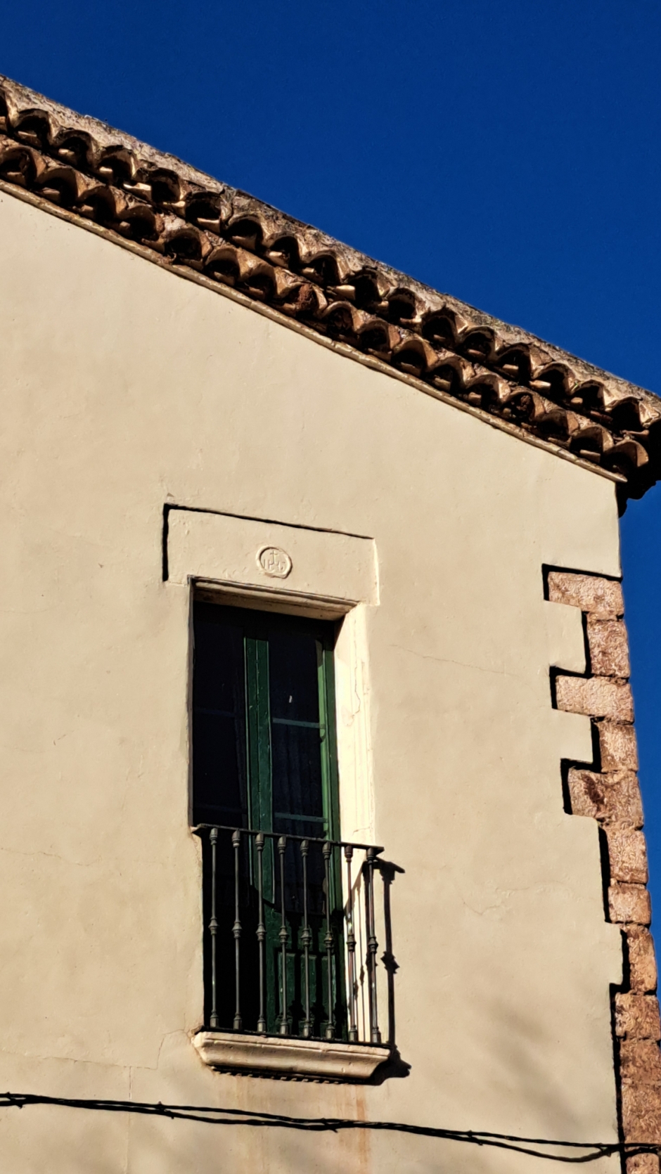 Detall de la llinda del balcó amb l'anagrama de Jesús inscrit a la llinda. 