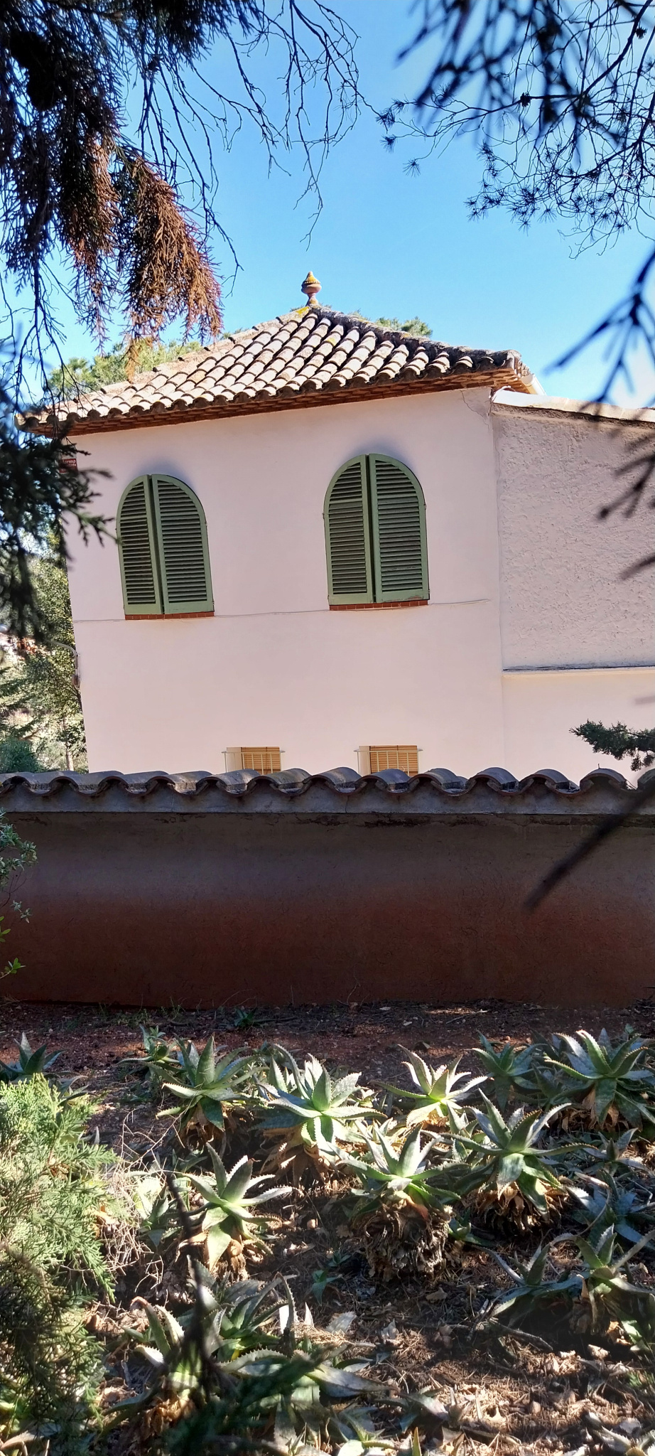 L'edifici de planta quadrada amb detall de la fusteria del tancament de les finestres en arc. 