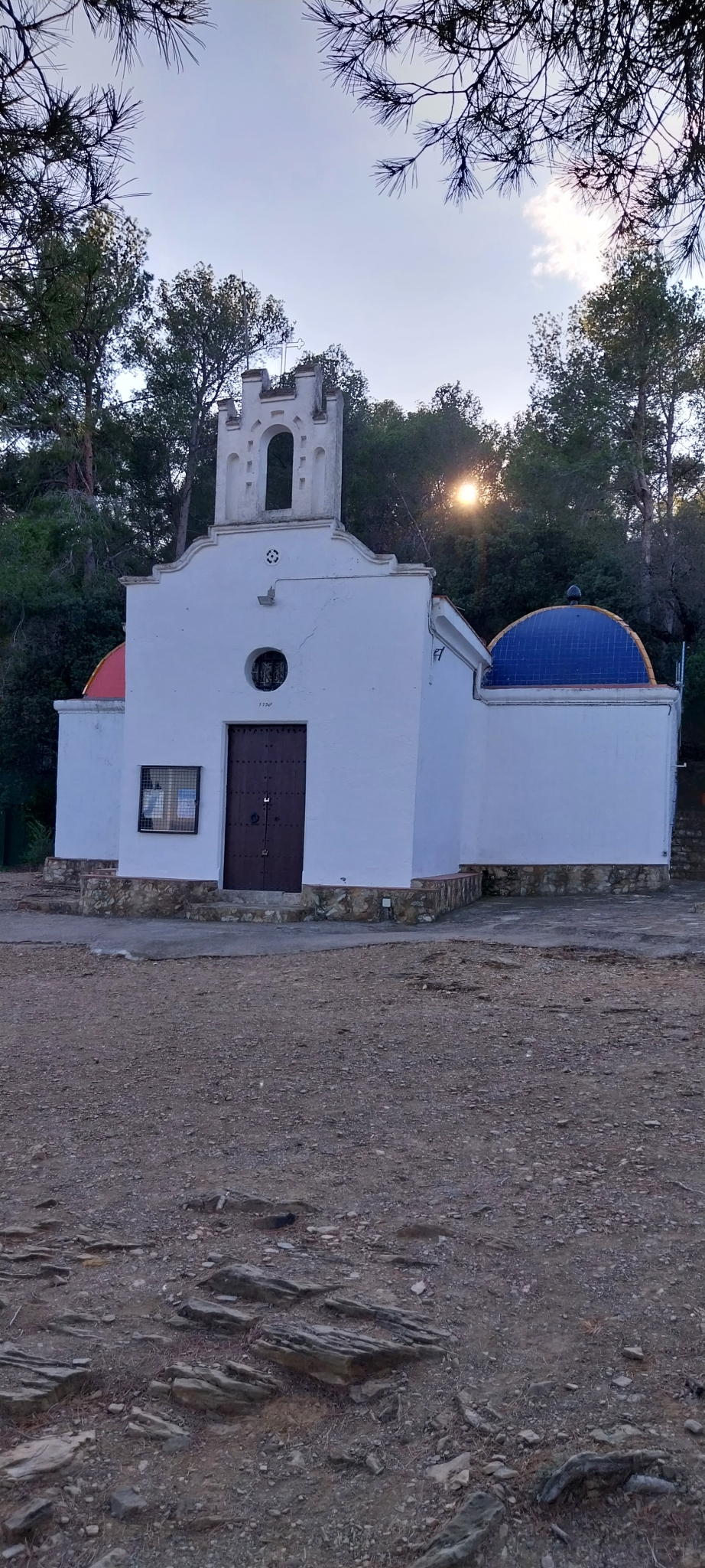 Lateral de l'edificació aixecada en un replà de la muntanya. Vista frontal de l'ermita.
