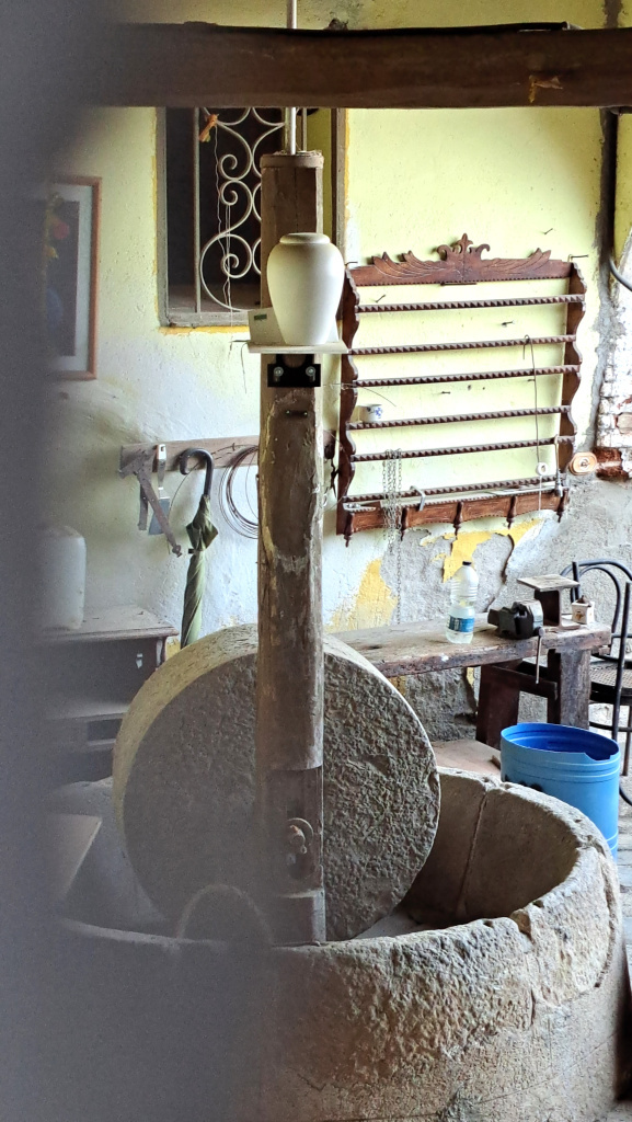 Trull d'oli sota el porxo mig cobert de l'interior.