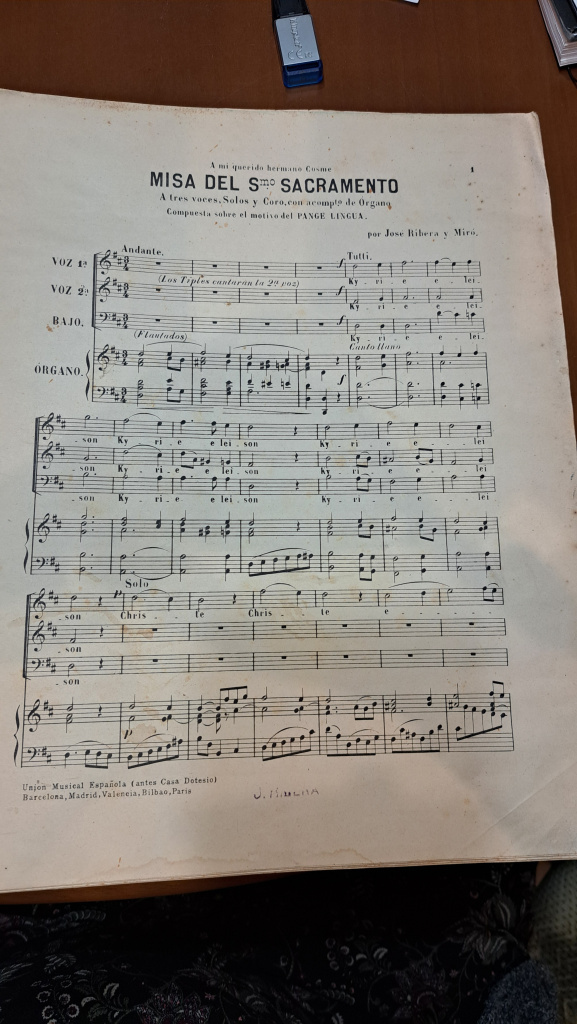 Primera pàgina de la partitura de la "Misa del Smo. Sacramento", dita de Ribera. La partitura està escrita per a tres veus (sols i cor) i inclou l'acompanyament d'òrgan. La distribució de les veus i les línies melòdiques són clarament visibles, oferint una estructura detallada per als intèrprets. Col·lecció particular.