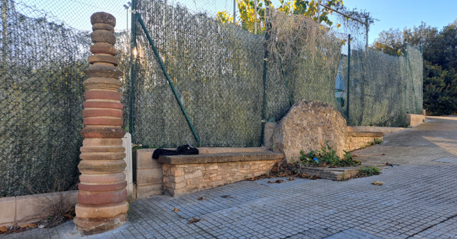 L'escultura en el seu entorn, al costat d'una font urbana que està fora de servei.