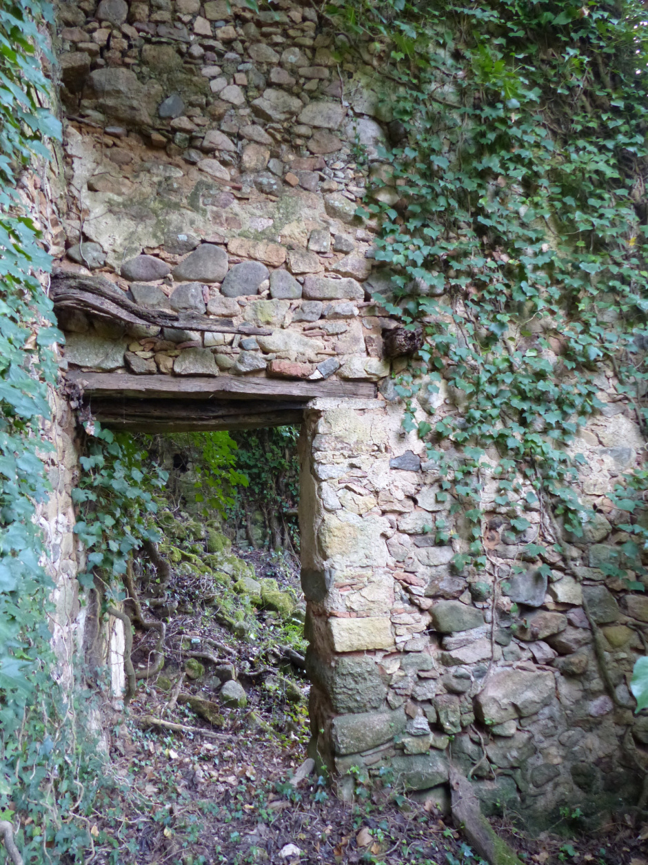 Can Mestric. Detall d'una porta amb el muntant de pedra i la llinda de fusta que encara es conserven dempeus.