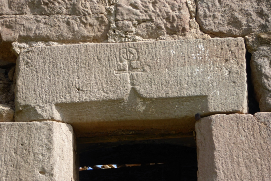 Llinda de la façana de ponent amb una creu i un símbol a la part superior