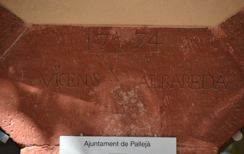 Inscripció "1774 / VICENÇ ALBAREDA" que es pot llegir entre els dos arcs escarsers del cos afegit