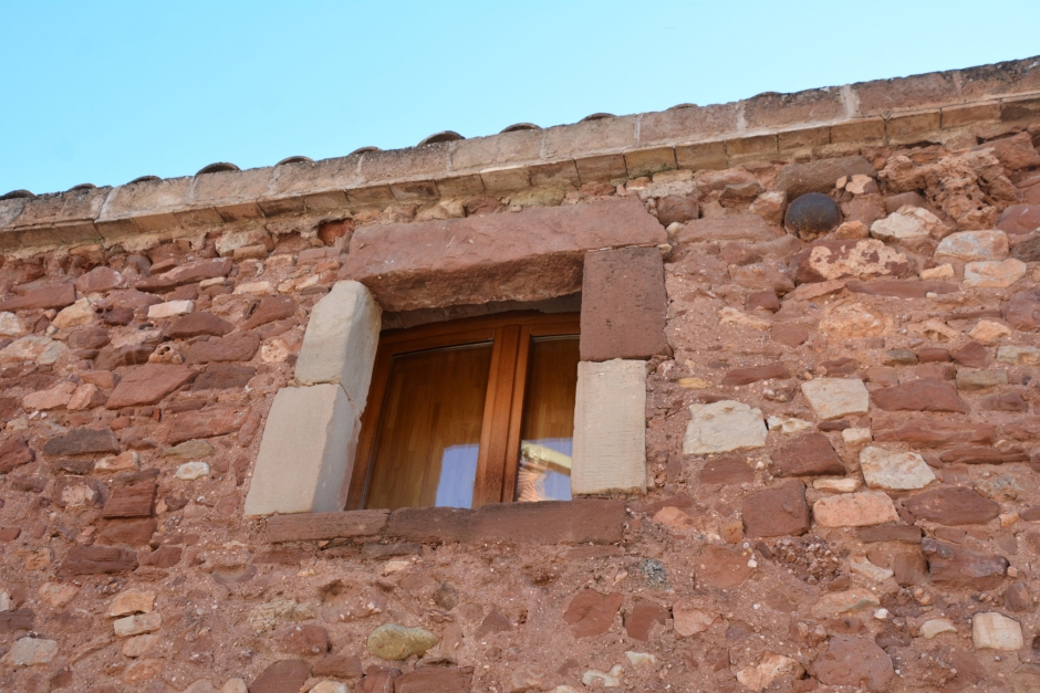 Detall de la finestra i de la bala de canó encastada a la façana lateral