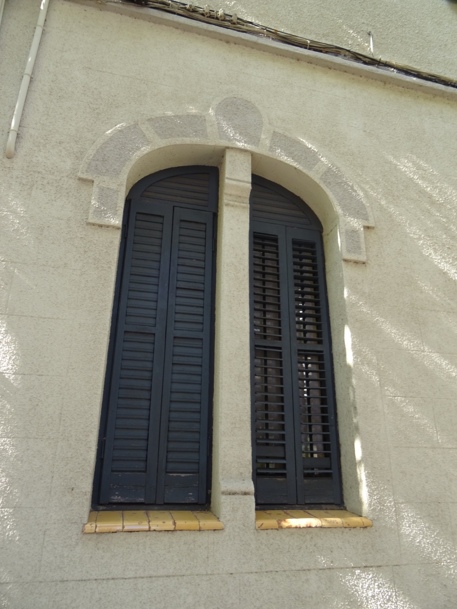 Detall d'un finestral de la primera planta amb un monjo al mig de la façana principal del Conjunt de Maria Llinàs II