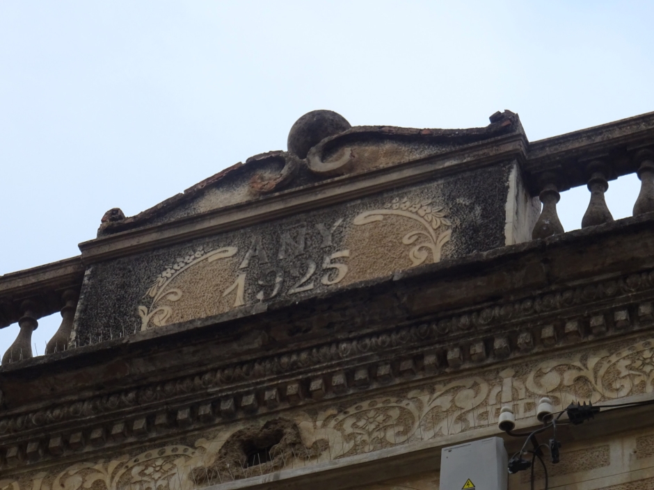 Cartel·la del coronament de la façana de la casa de Pere Jané.