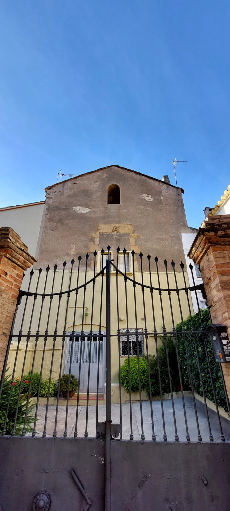 Detall de la façana amb la porta de ferro de tancament del barri.