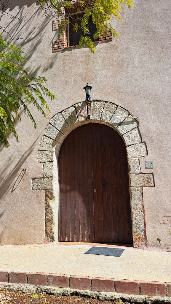 Detall de la porta de pedra treballada i d'arc rodó. A esquerra, l'agarrador circular per a les bèsties.