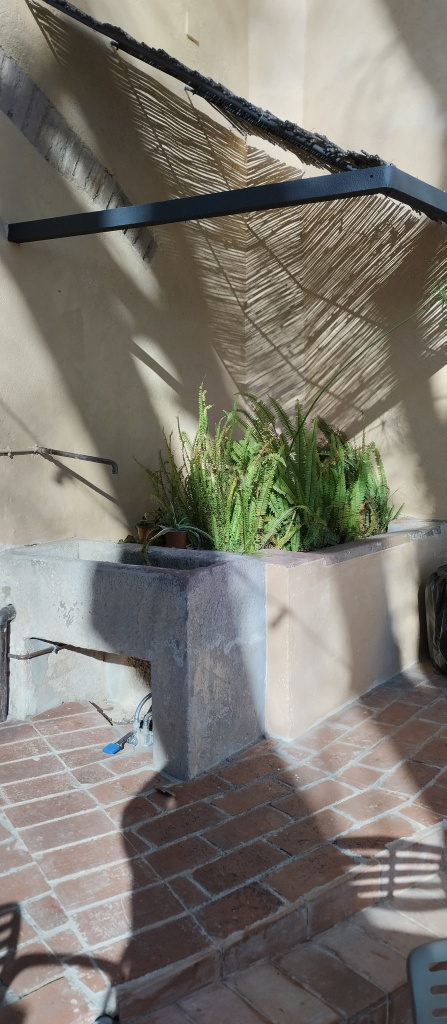 Vista de la font i el safareig al racó del pati de la masia.