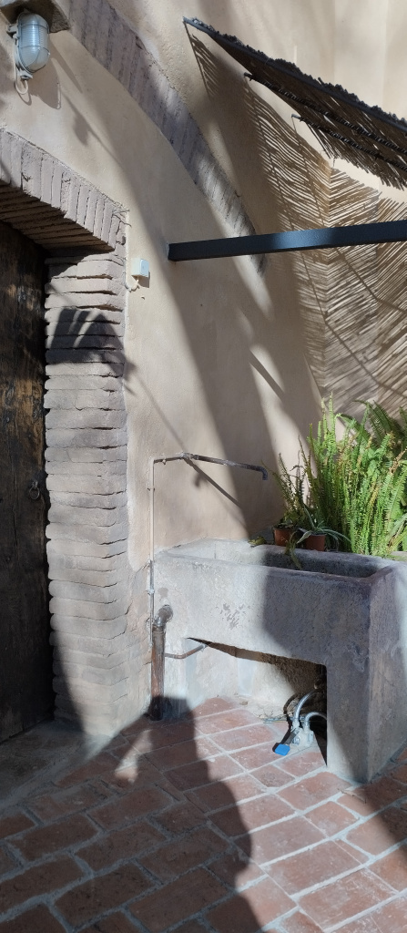 Vista de la font i el safareig al racó del pati de la masia.