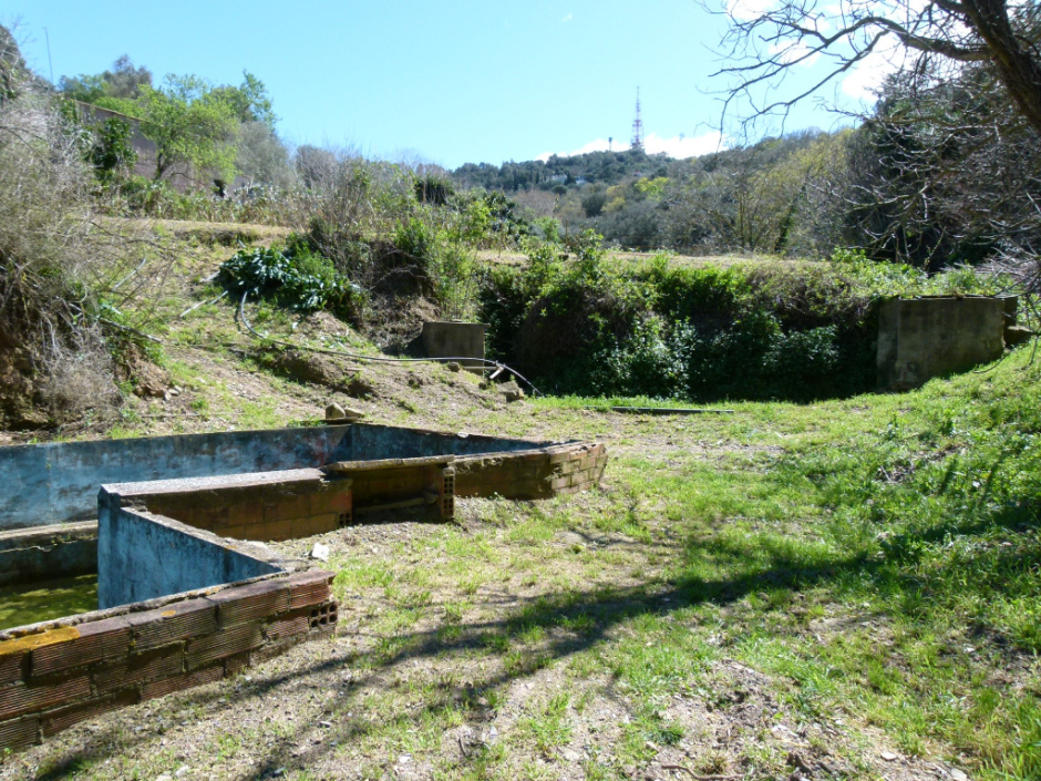 Vista general de l'emplaçament de la portella de la mina al fons a l'esquerra. En primer terme, la bassa que acumula l'aigua per regar els horts. 