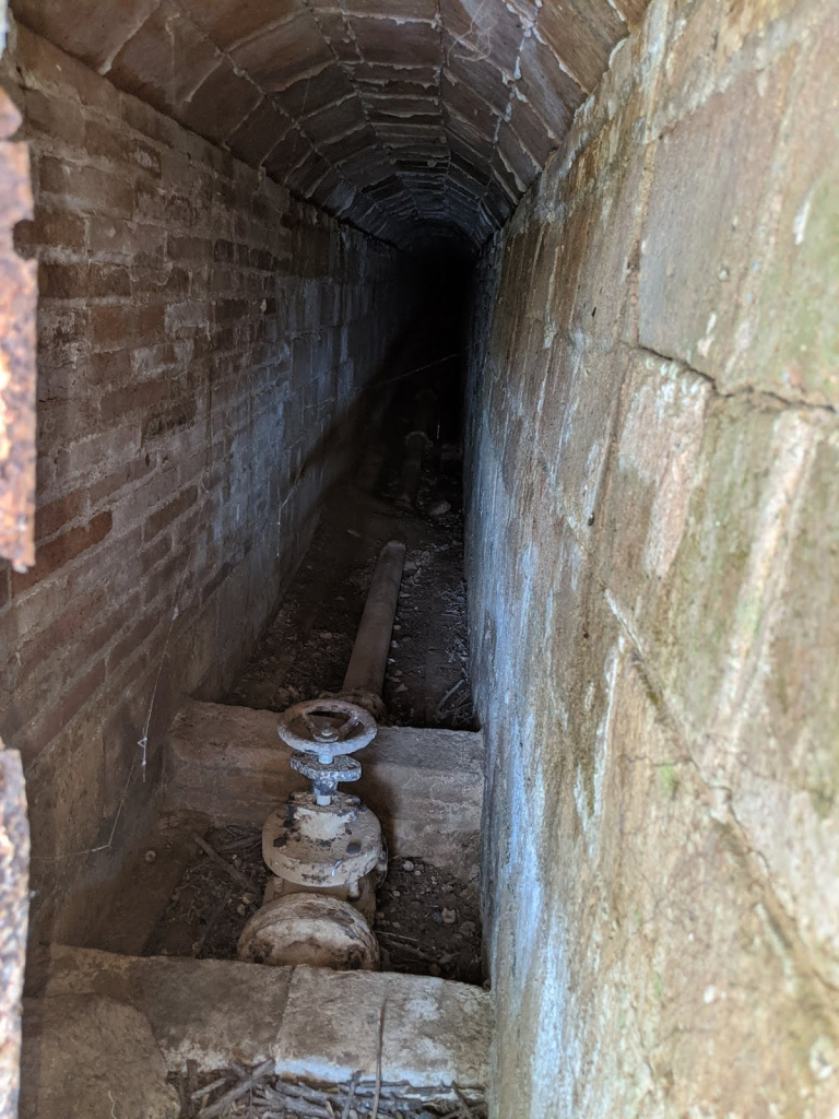 Vista de l'interior de la galeria de la mina, amb la canonada de ferro que extreu l'aigua de la bassa. Font: Fes Fonts Fent Fonting.