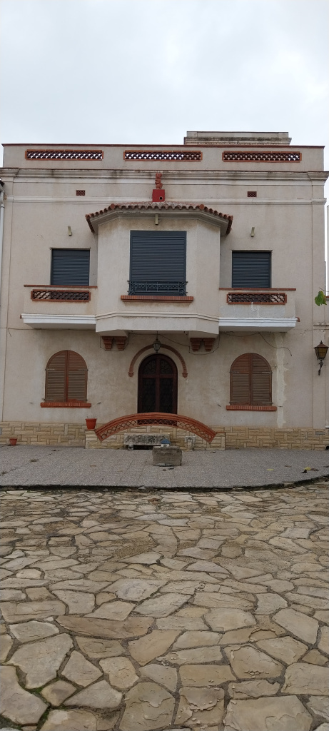 Vista detall del cos central de la façana i del pati pavimentat.