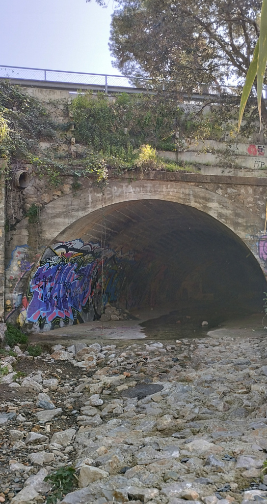 Vista detall de l'arc del pont i la llera de la riera de Sant Just en el seu tram no soterrat.