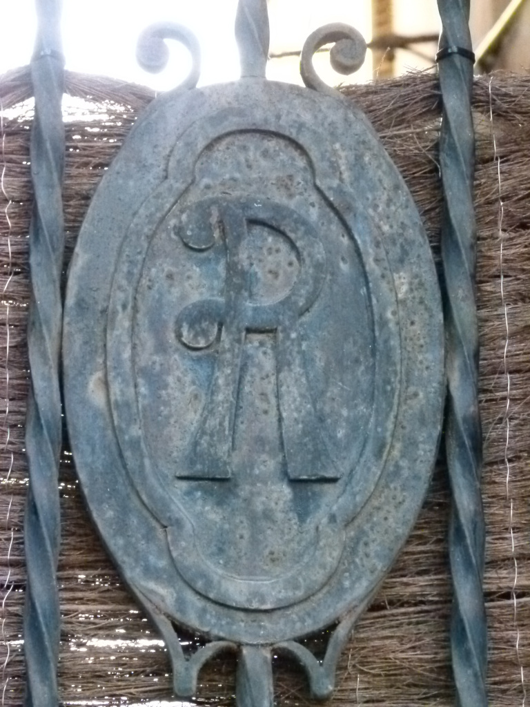 Inicial R situada a la reixa de forja d'entrada a la finca.