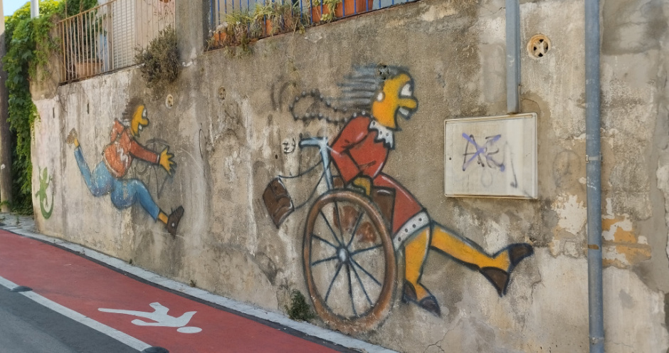 Grafit del carrer Bonavista pintat l'any 2024, relacionat amb l'original del carrer Badó. Després de trenta-sis anys, el fill és ara el que corre darrere de la cadira de rodes de la seva mare.