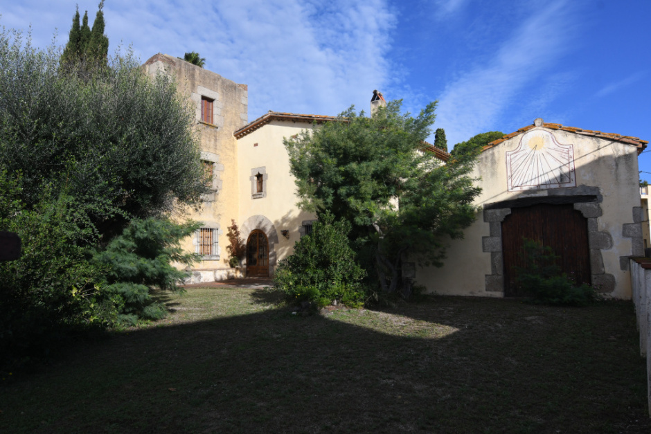 Vista general de can Sauri amb la casa, la torre i el rellotge de sol a la cotxera. 