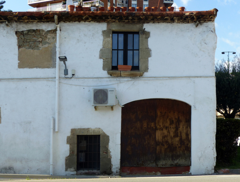 Vista general de la casa amb el rellotge a mà esquerra, dessota el ràfec. 