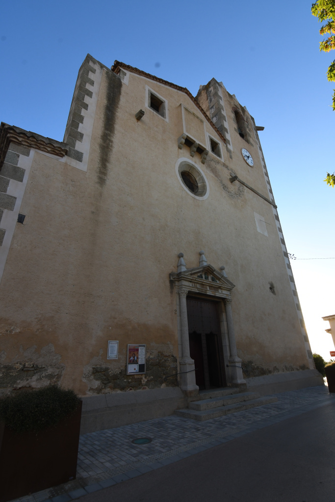 Vista general de l'església amb el rellotge de sol dessota la torre del campanar. 