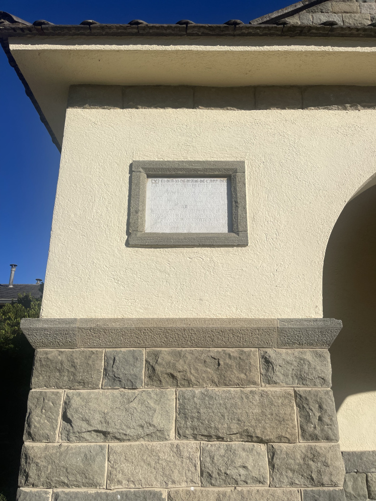 Placa amb la inscripció referent a la inauguració de l'església nova. Escriptura d'imitació de tipus medieval. Font: Fotografia pròpia.